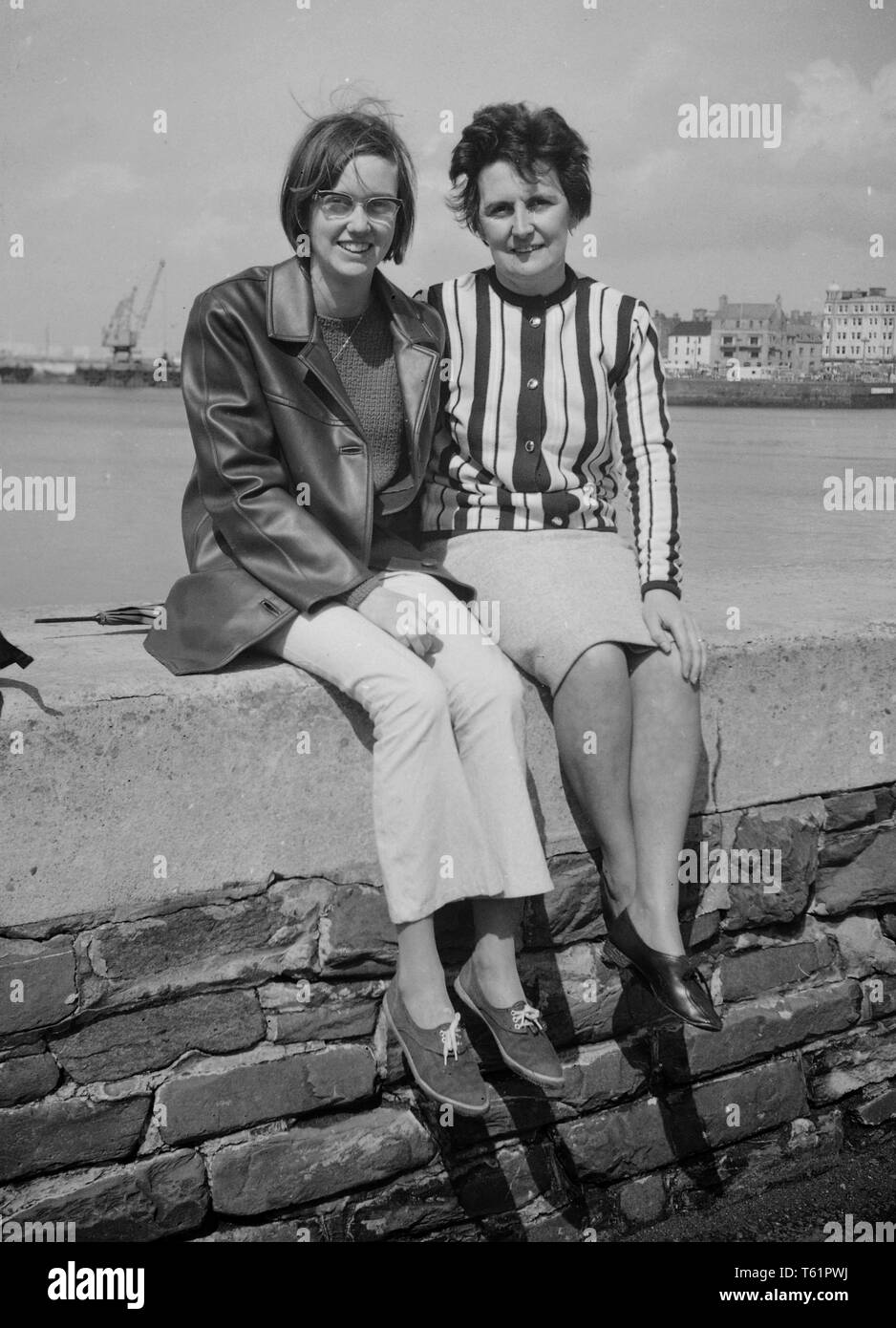 Madre e figlia in posa su una parete del porto in mode del tempo.  Fotografia amatoriale da una collezione di famiglia in vacanza al mare in  Inghilterra. c1950 Foto di Tony Henshaw