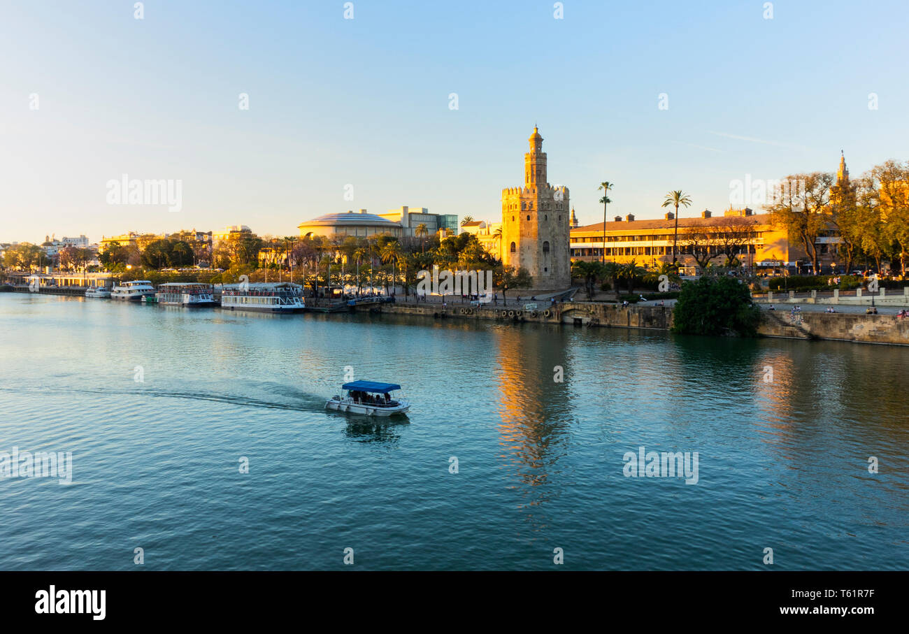 Il sole di setting trasforma la Torre del Oro a un ricco colore dorato a Siviglia Foto Stock