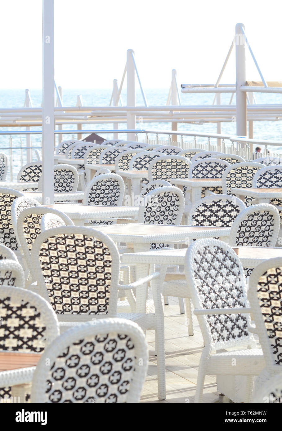 Bianco mobili di plastica in un cafè sulla costa prima dell' inizio della stagione di spiaggia Foto Stock