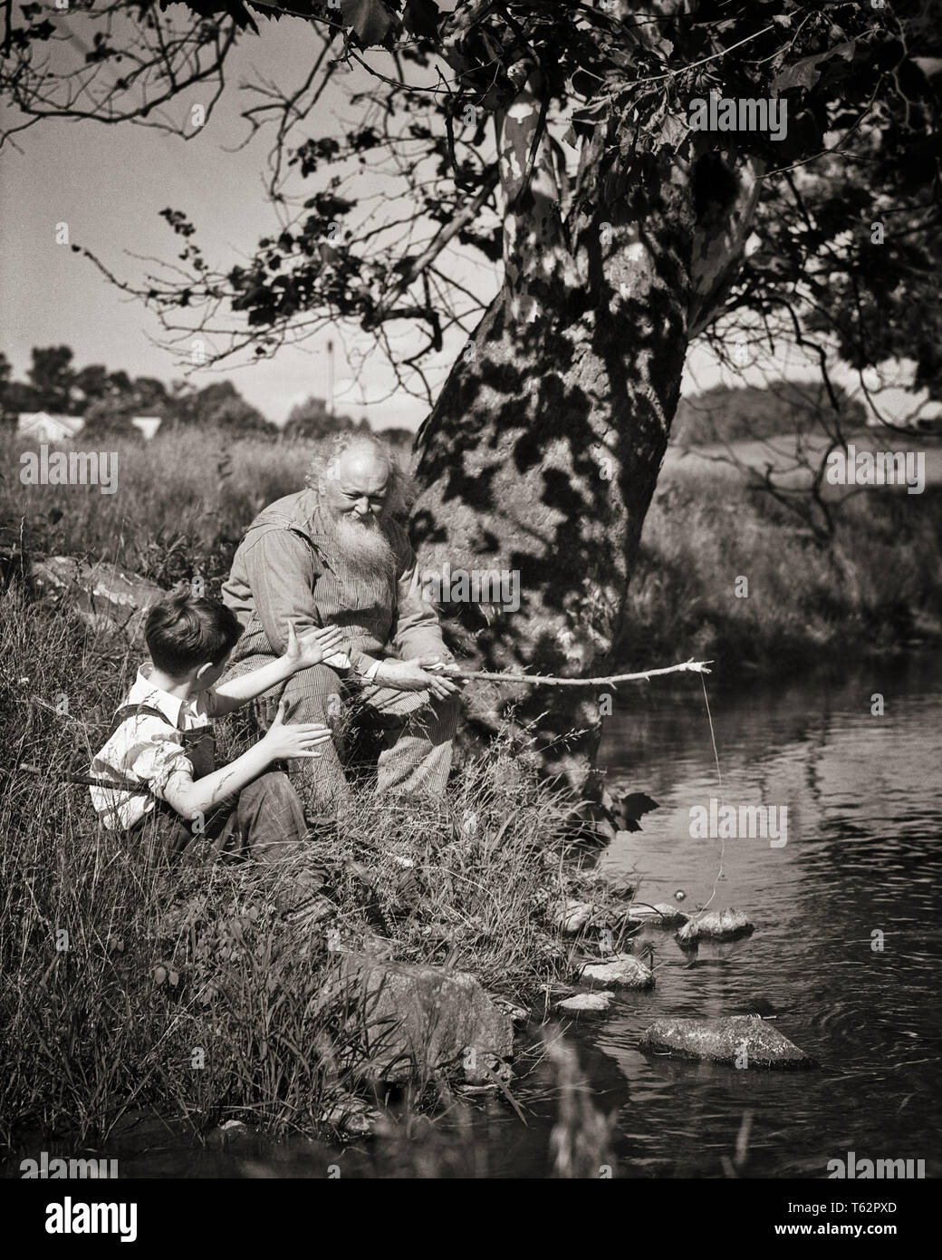 1930s BOY e nonno condividendo storie mentre la pesca nel flusso - un3296 HAR001 HARS FLUSSO DI PERSONE DI SESSO MASCHILE SENIOR UOMO NIPOTI ADULTI SENIOR B&W ESTATE FELICITÀ OLDSTERS avventura antica di svago e di ricreazione anziani storie nipoti nonni nipote ANGLING uomo anziano crescita novellame BIANCO E NERO etnia caucasica nonno HAR001 in vecchio stile Foto Stock