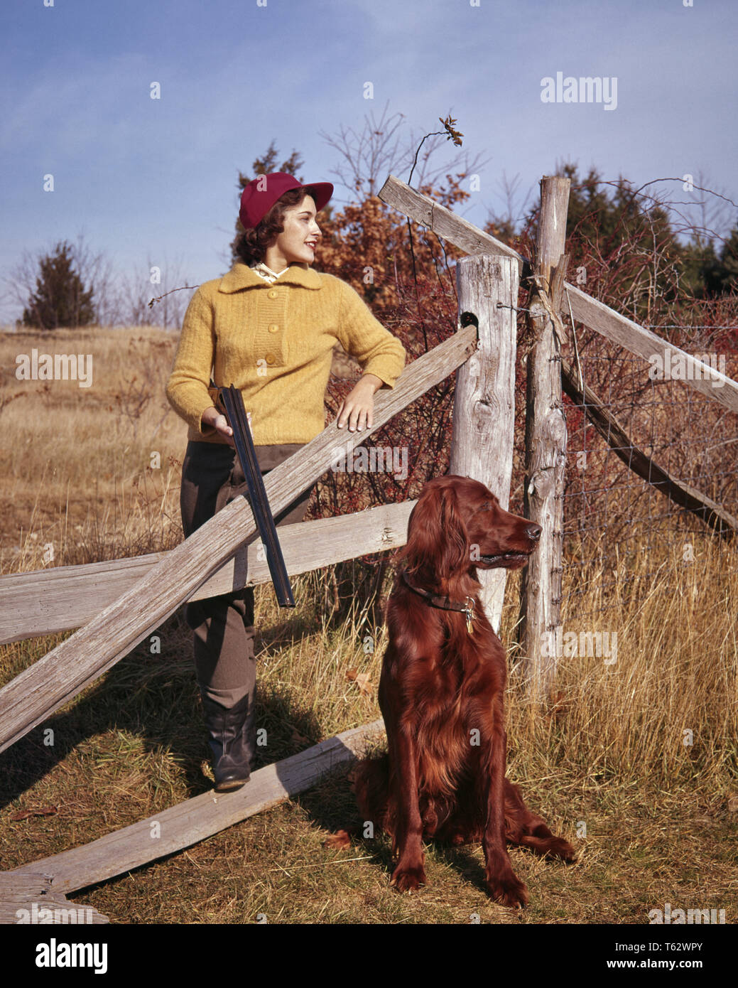 Anni Cinquanta donna UPLAND BIRD HUNTER cappuccio rosso maglione giallo appoggiato sulla recinzione di legno AZIENDA PAESE SHOTGUN LIFESTYLE setter irlandese cane - kg3247 legge001 HARS rilassante stile di vita irlandese femmine rurale salubrità cresciuto spazio copia a tutta lunghezza LADIES PERSONE CRESCIUTI HUNTER FIDUCIA Tempo di suoneria fuori la gente abilità STORIA ATTIVITÀ STRUTTURA divertimenti felicità mammiferi avventura di viaggio HOBBY INTERESSE CANINI GETAWAY HOBBY conoscenza basso angolo passatempo ricreazione setter di piacere sulle vacanze POOCH SPLIT RAIL setter irlandese elegante appoggia UPLAND CANINE ARMA ARMI DA FUOCO GUNNING MAMMIFERO MID-adulto metà donna adulta RELAX Foto Stock