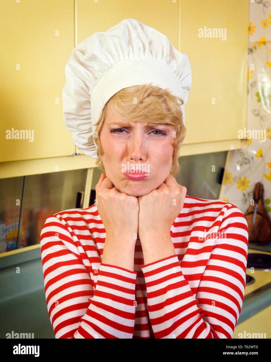 Anni Settanta sconvolse Busbana francese donna che indossa lo chef HAT TOQUE a strisce rosse camicia bianca IN CUCINA ACCIGLIATA mani sul mento guardando telecamera - kg5583 HAR001 HARS paura bionda comunicazione giovani adulti femmine LIFESTYLE STRIPED MOODY HOME vita di metà lunghezza LADIES persone tormentate espressioni accigliata tristezza contatto visivo disastro massaia casalinghe Busbana francese in casalinghe umore GLUM concettuale deluso fallimento miserabile TOQUE giovane donna adulta etnia caucasica HAR001 in vecchio stile Foto Stock