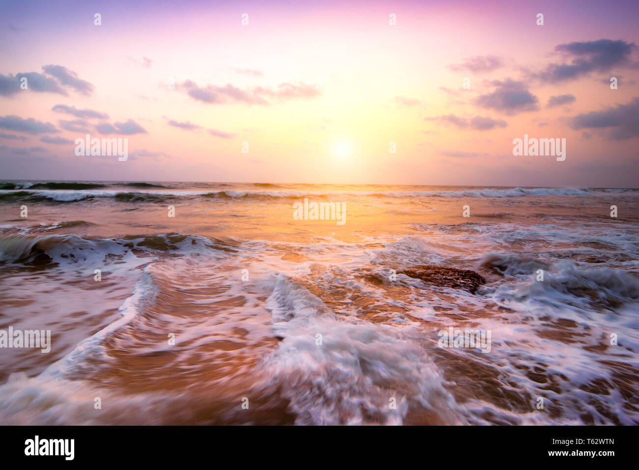 Fantastici colori della tempesta tropicale tramonto a spiaggia sabbiosa. Costa dell'oceano sotto il sole di sera. India del sud paesaggio Foto Stock