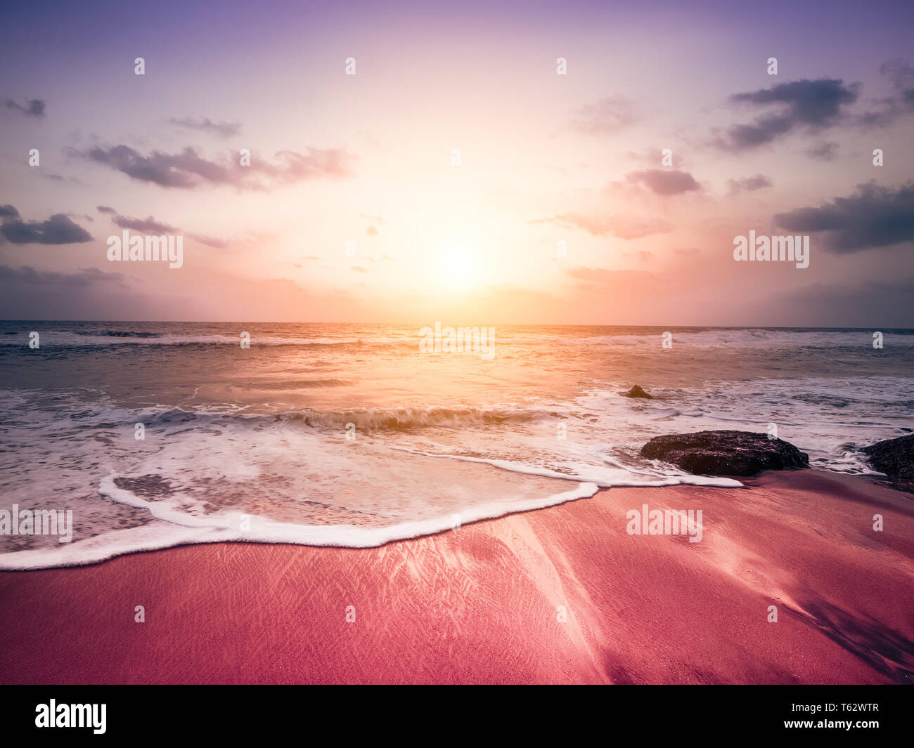 Fantastici colori del tramonto tropicale presso la spiaggia di sabbia. Rocce alla costa dell'oceano sotto il sole di sera. India del sud paesaggio Foto Stock