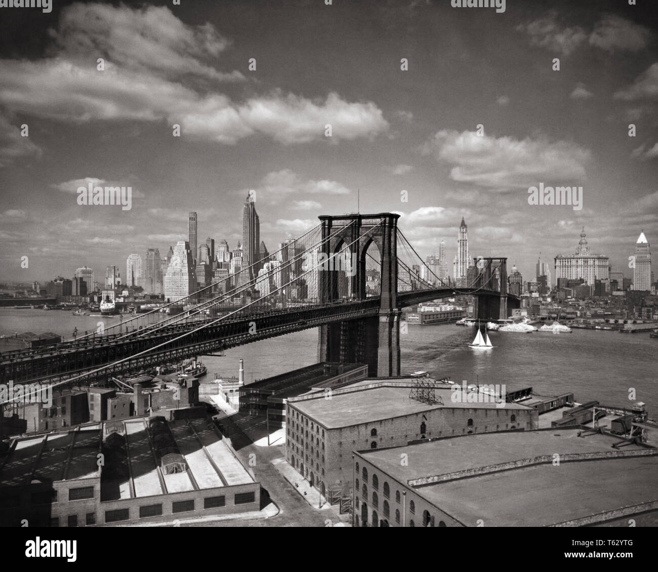 1930s NEW YORK CITY ponte di Brooklyn e la skyline di Manhattan inferiore attraverso l'East River - Q36336 CPC001 HARS IN BIANCO E NERO di ponti Ponte di Brooklyn East River Financial District di Manhattan in vecchio stile grattacieli in sospensione Foto Stock