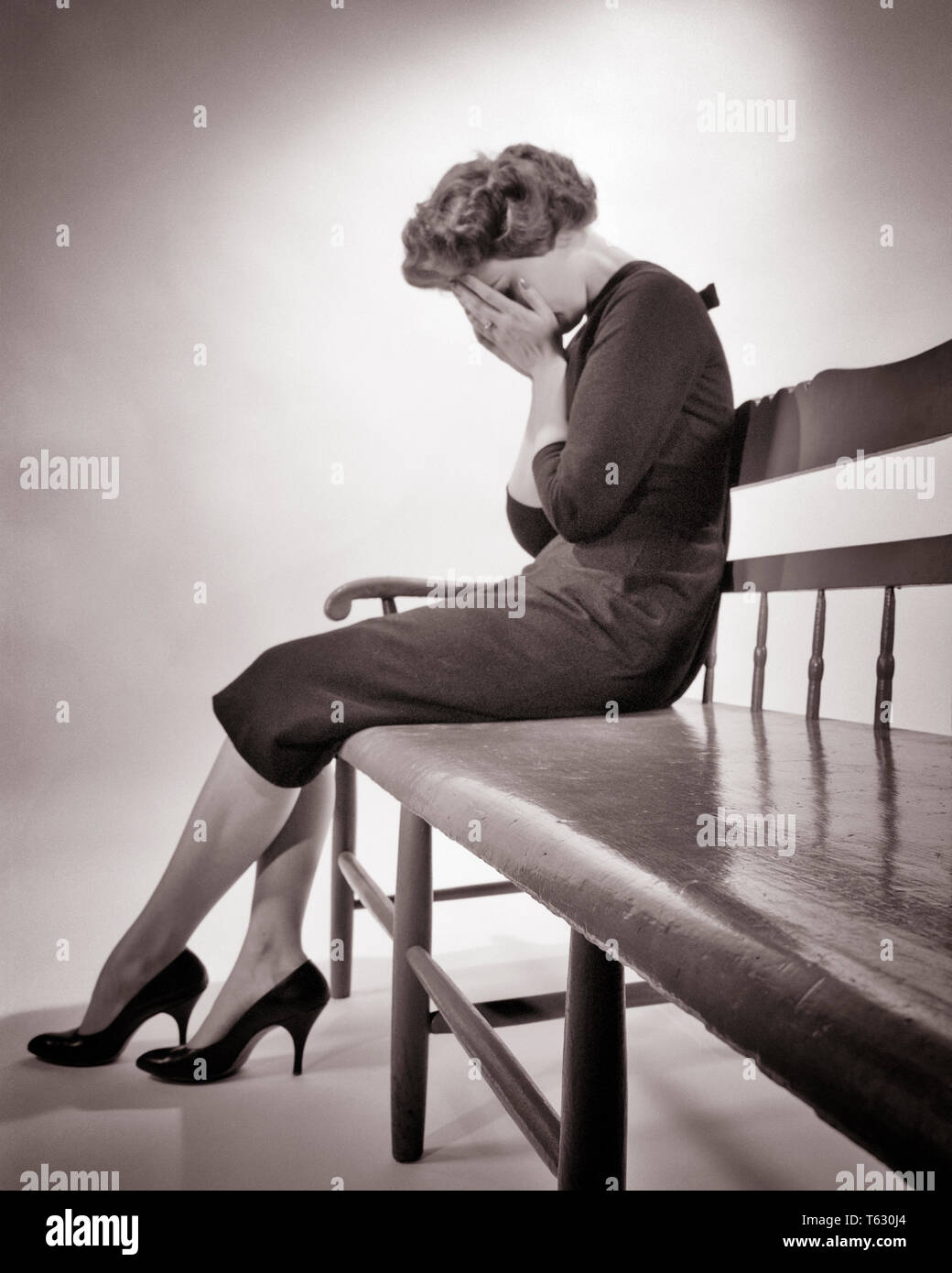 Anni Cinquanta stagliano sconvolta donna seduta sul banco di piangere tenendo le mani sulla faccia tristezza depressione perdita - S3493 HAR001 HARS angolo basso potente umore dolore imbarazzato addolorate concettuale GUASTO GLUM MID-adulto metà donna adulta misero in bianco e nero di etnia caucasica HAR001 in vecchio stile Foto Stock