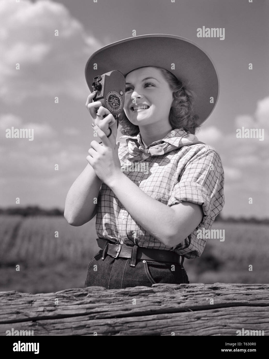 1940s sorridente giovane donna nel cappello da cowboy e western vestiti di fotografare utilizzando tenuto in mano 8MM HOME MOVIE CAMERA - u532 HAR001 HARS HOBBY INTERESSE PER IL TEMPO LIBERO E IL DIVERTIMENTO HOBBY conoscenza passatempo ricreazione a fotografare il piacere di sorrisi utilizzando concettuale elegante gioiosa 8MM tenuto in mano il rilassamento giovane donna adulta AMATORIALE IN BIANCO E NERO di etnia caucasica GODIMENTO HAR001 in vecchio stile Foto Stock