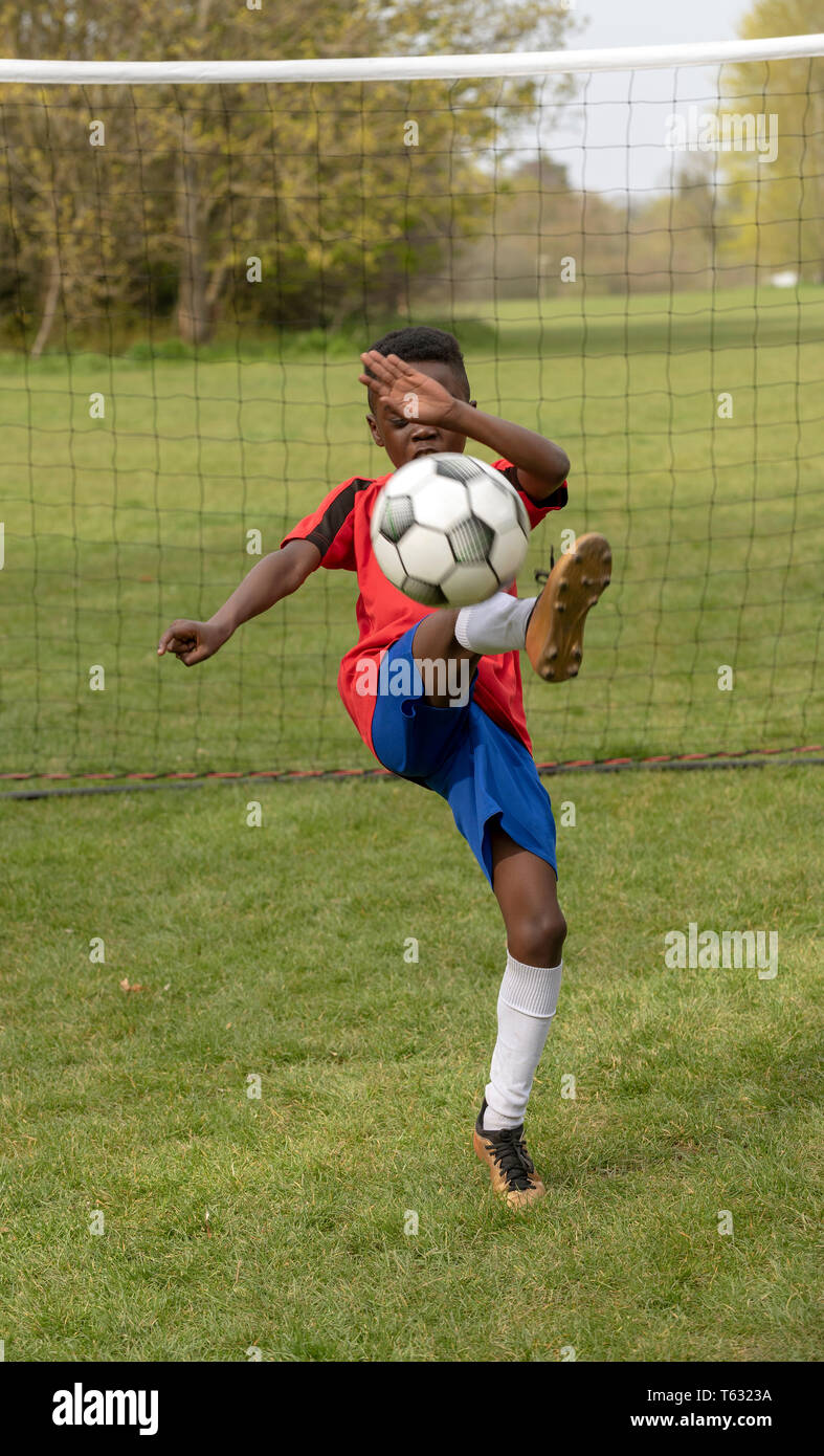 Hampshire, Inghilterra, Regno Unito. Aprile 2019. Un giovane giocatore di football per difendere l'obiettivo durante una sessione di formazione in un parco pubblico. Foto Stock