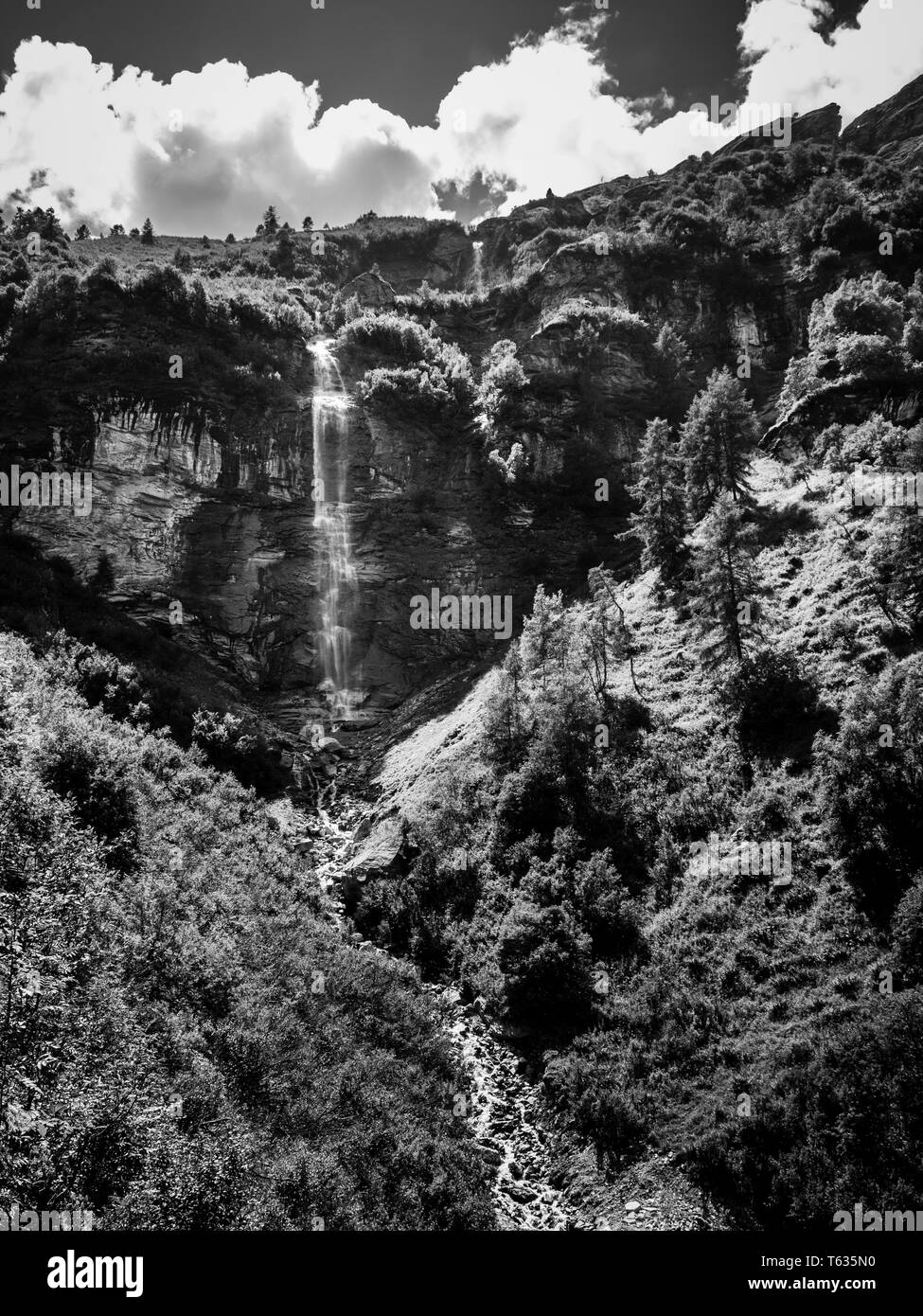 Una piccola cascata vicino villaggio alpino Zinal in Val d'Anniviers nelle Alpi Pennine nel canton Vallese, Svizzera. In bianco e nero fine art Foto Stock