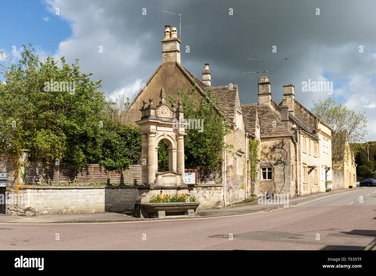 La Fontana Mayo Memorial con cottage in pietra sullo sfondo, High Street, Corsham, Wiltshire, Inghilterra, Regno Unito Foto Stock