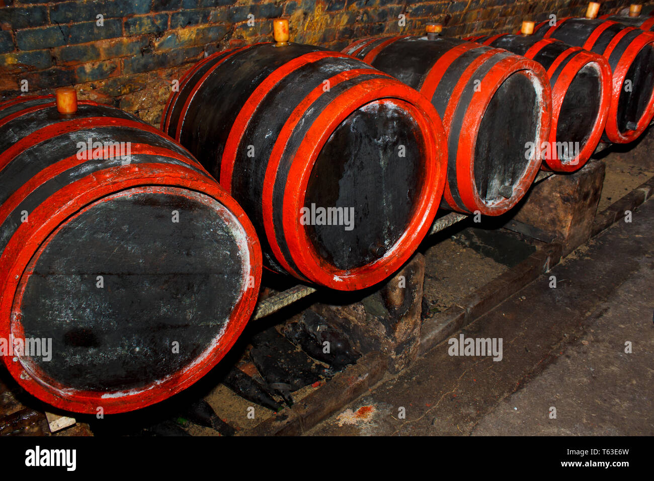 Botti da vino impilati nella vecchia cantina dell'azienda vinicola Foto Stock