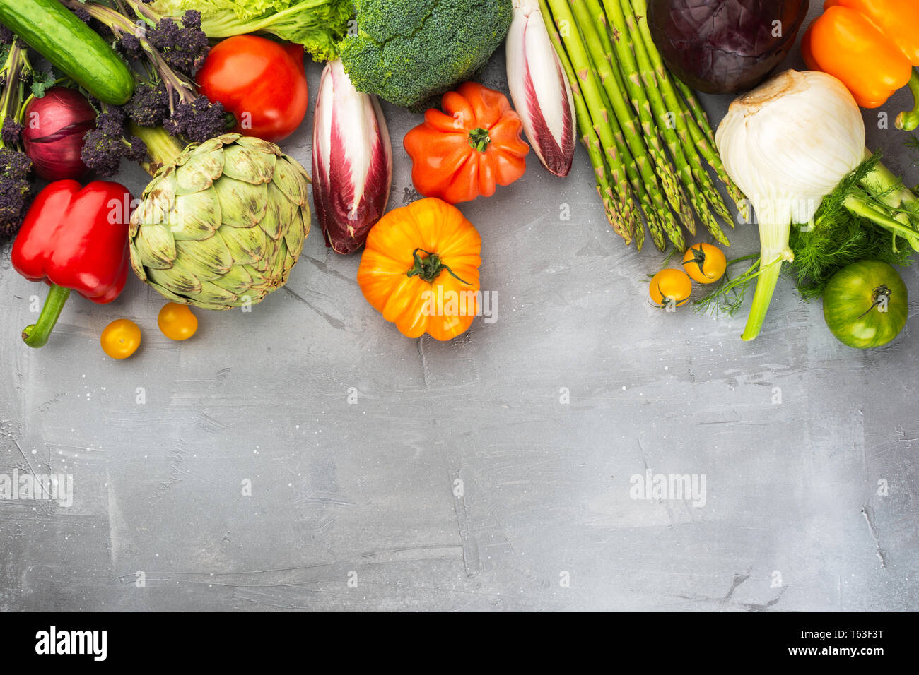 Fresche verdure crude sul cemento grigio Sfondo, vista dall'alto, copia di spazio, il fuoco selettivo Foto Stock