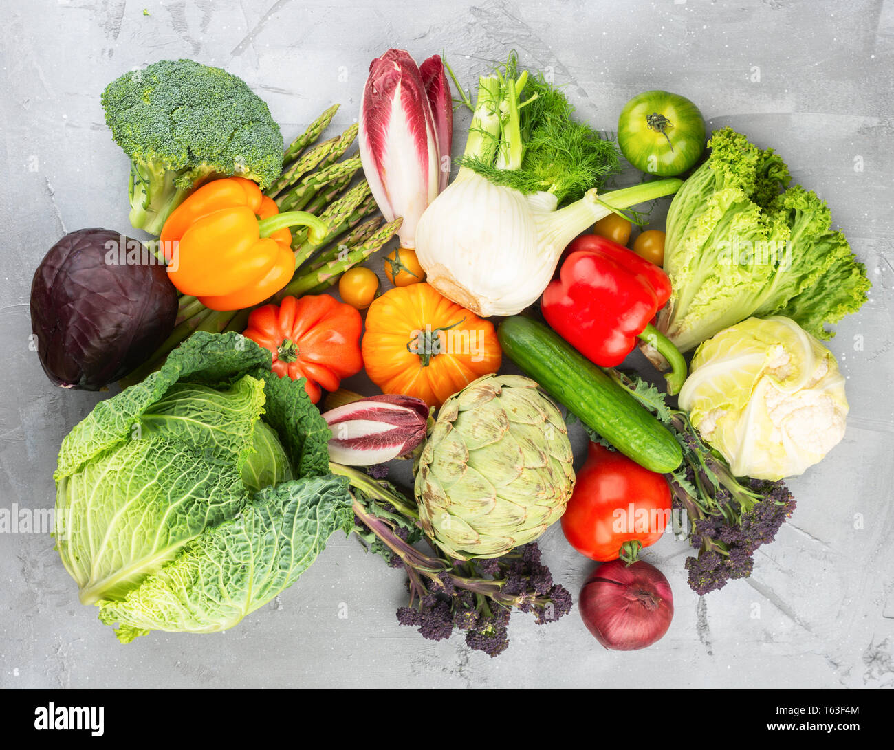 Fresche verdure crude sul cemento grigio Sfondo, vista dall'alto, copia di spazio, il fuoco selettivo Foto Stock