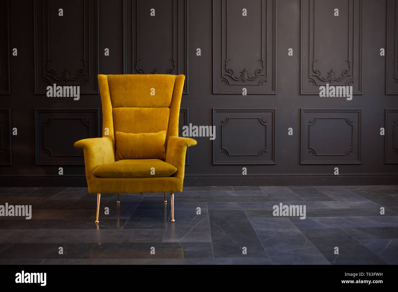 Elegante di colore giallo brillante cattedra contro un grigio scuro muro. Elegante sedia sulla parete di sfondo, copia, lo spazio interno alla moda. Foto Stock