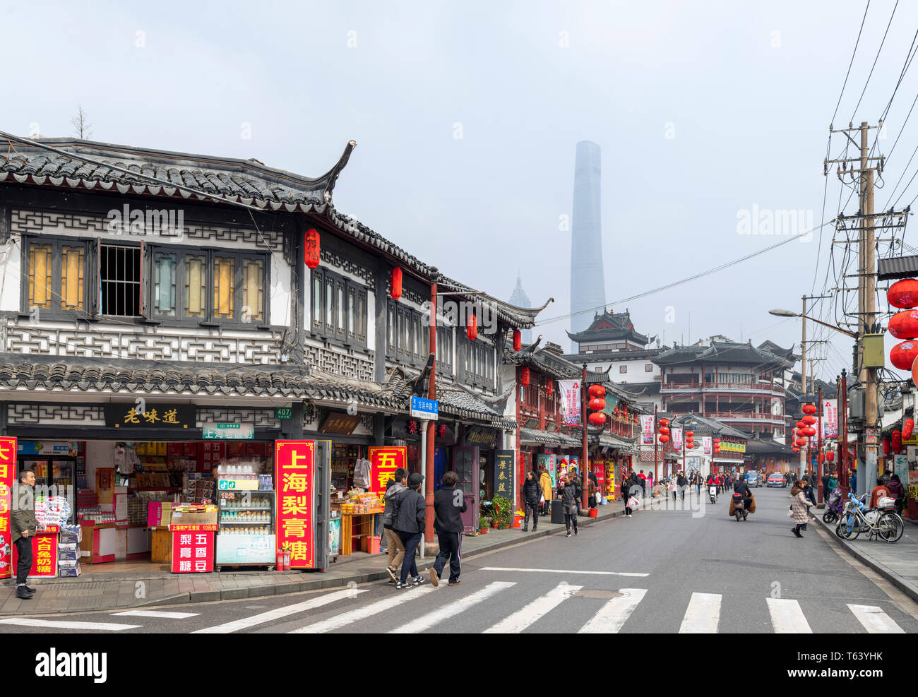 Negozi Tradizionali e ristoranti sul Medio Fangbang Road con la Shanghai Tower, appena visibile attraverso l'inquinamento atmosferico, la Città Vecchia, Shanghai, Cina Foto Stock