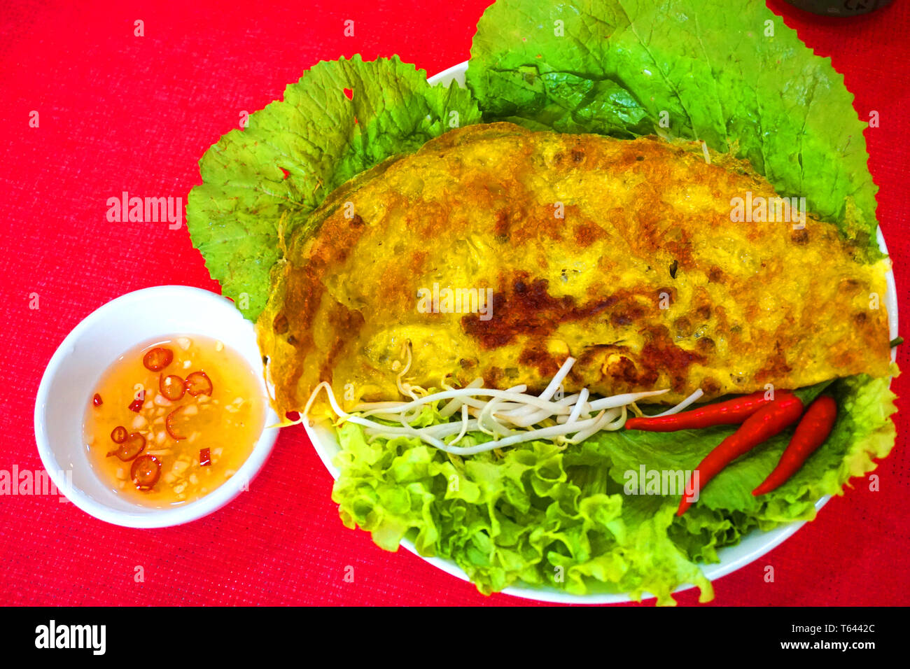 Banh xeo - vietnamita tradizionale cibo di strada giallo croccante di farina di riso dolce con gamberi a fungo Mung bean germoglio sfrigolanti torta con salsa di pesce chili Foto Stock