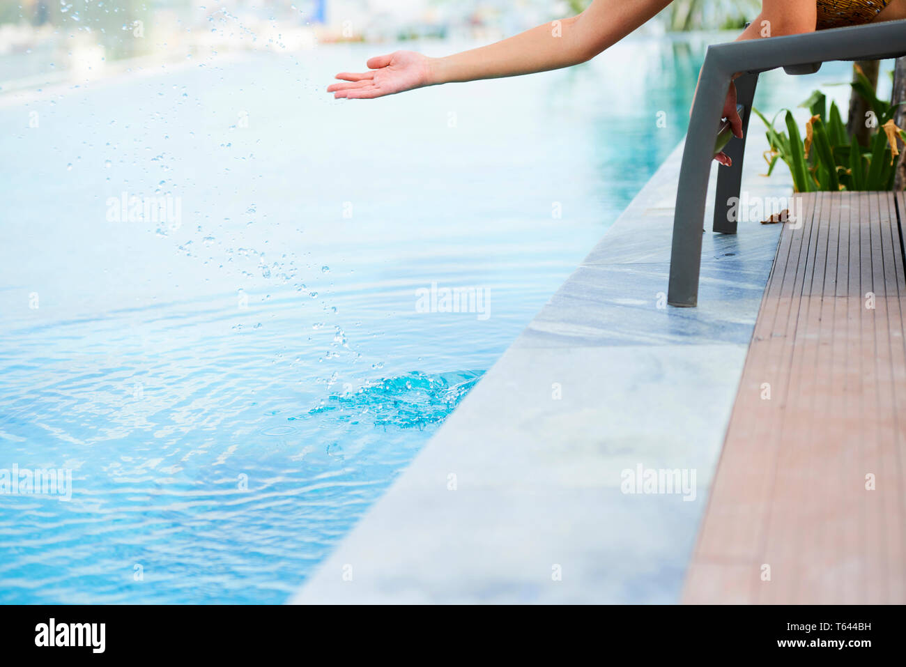 Donna di toccare acqua nella piscina Foto Stock