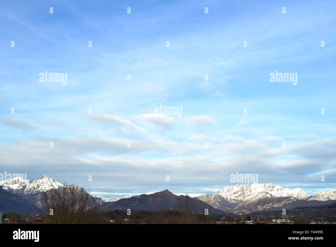 Vista panoramica da Molteno al massiccio della Grigna e del Resegone mountain range crest coperte di neve in inverno e una grande luce blu cielo cloudscape. Foto Stock