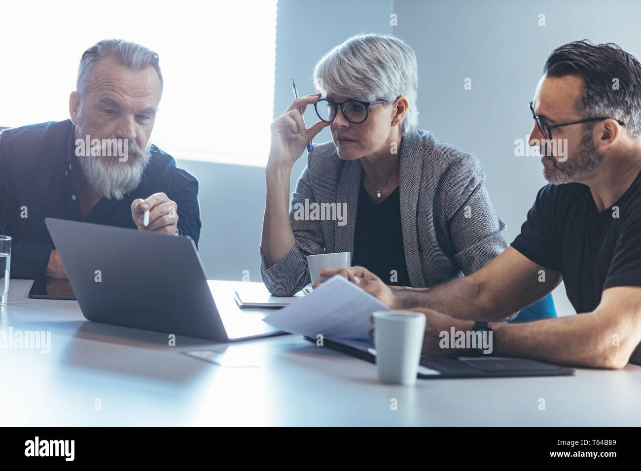 La gente di affari presso la sala conferenze guardando il laptop. Team aziendale riunione in ufficio. Foto Stock