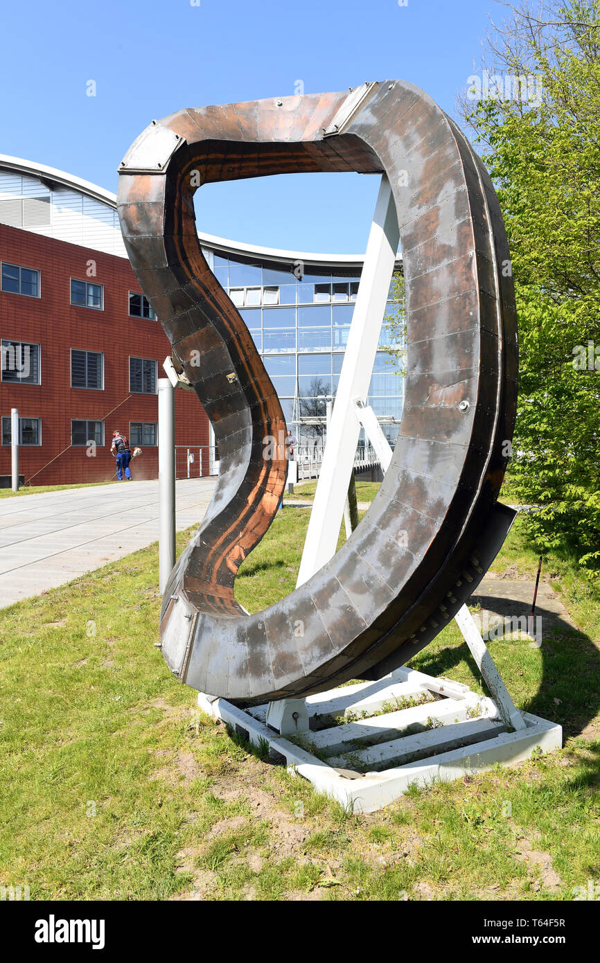 Greifswald (Germania). 26 apr, 2019. Una bobina si erge davanti all'ingresso principale dell'Istituto Max Planck per la fisica del plasma in Greifswald. L'istituto con il reattore a fusione 'Wendelstein 7-X' si concentra sulla fusione nucleare come una possibilità di generazione di energia. Credito: Stefan Sauer/dpa-Zentralbild/ZB/dpa/Alamy Live News Foto Stock