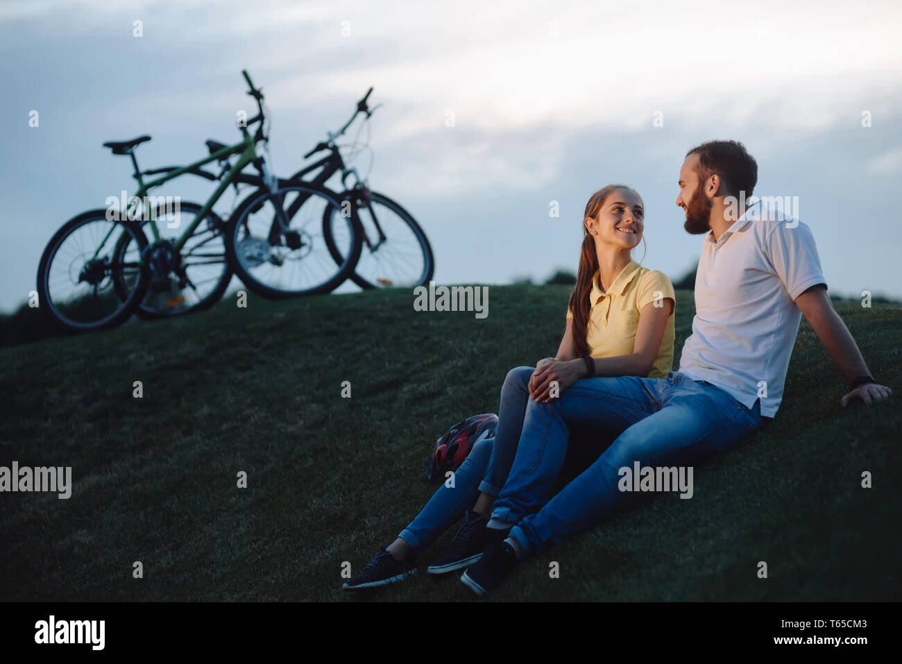 Paio di ciclisti in amore in appoggio su una verde collina. Foto Stock