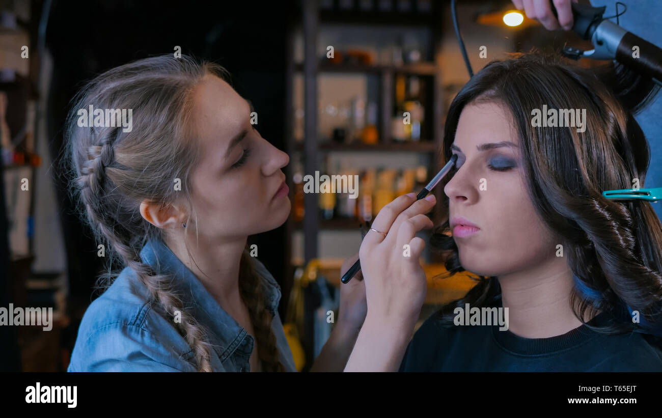 Make-up artist e parrucchiere lavora con client di donna Foto Stock