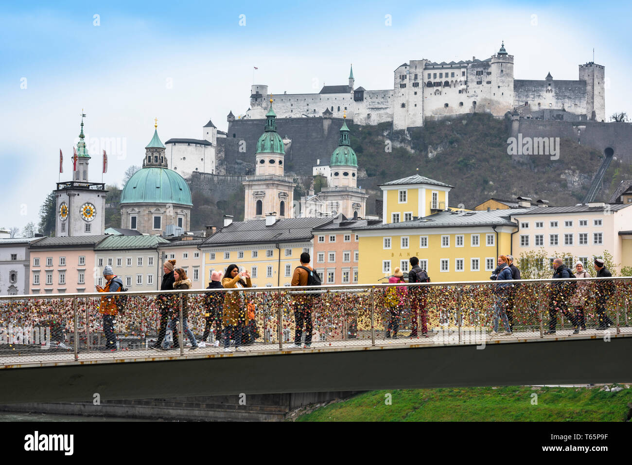 Makartsteg Salisburgo, vista dei turisti sul ponte Makartsteg guardando l'architettura della vecchia barocca e la sua collina del castello medievale. Foto Stock