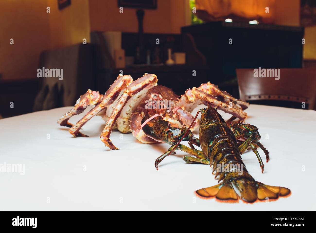 Re granchi e aragoste vive uno opposto all'altro su uno sfondo bianco. giacente sul tavolo contro lo sfondo del ristorante Foto Stock