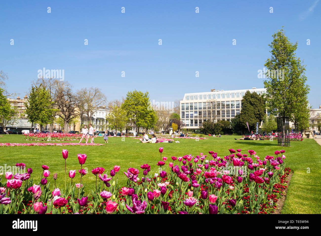 Letti di fiori e le persone aventi un pic-nic in Piazza Imperiale e il giardino imperiale Cheltenham Spa Gloucestershire England Regno Unito GB Europa Foto Stock