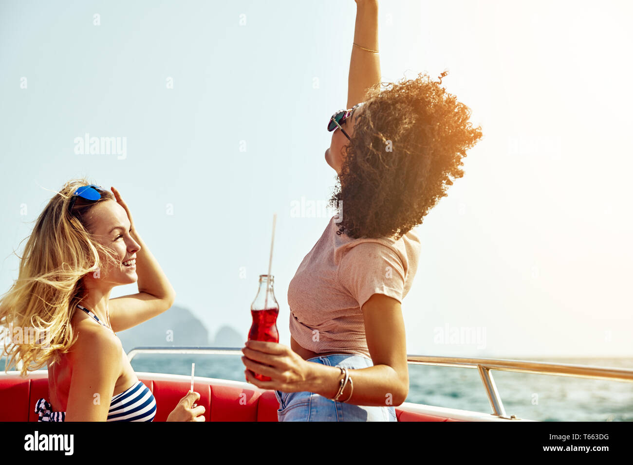 Due carefree giovani amici avente un buon tempo insieme su una barca in mezzo al mare durante le vacanze estive Foto Stock