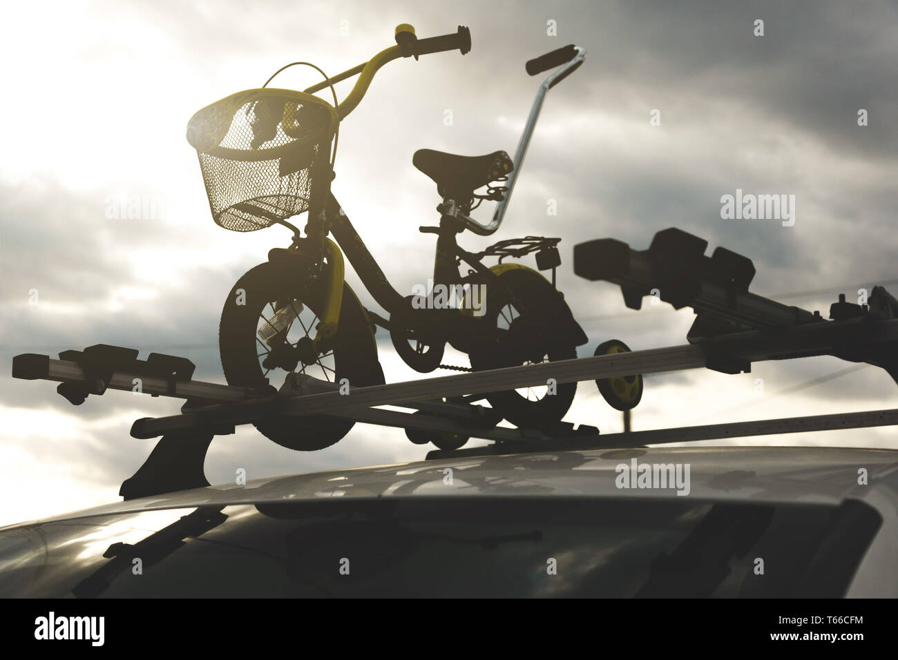 Il trasporto della bicicletta - di un bambini bicicletta sul tetto di una vettura contro il cielo in un montaggio speciale per il ciclismo. La decisione di trasportare grandi Foto Stock