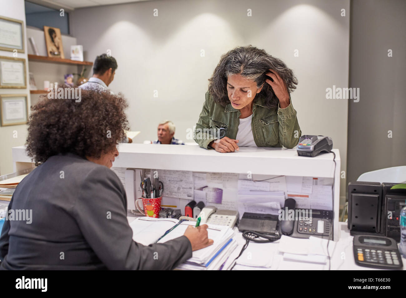 Paziente femmina di ripianificazione con receptionist in clinica Foto Stock