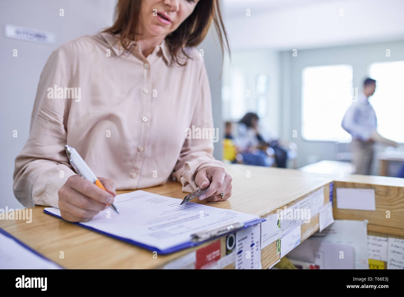 Donna con carta di credito la compilazione di assicurazione medica di documenti cartacei in clinica Foto Stock