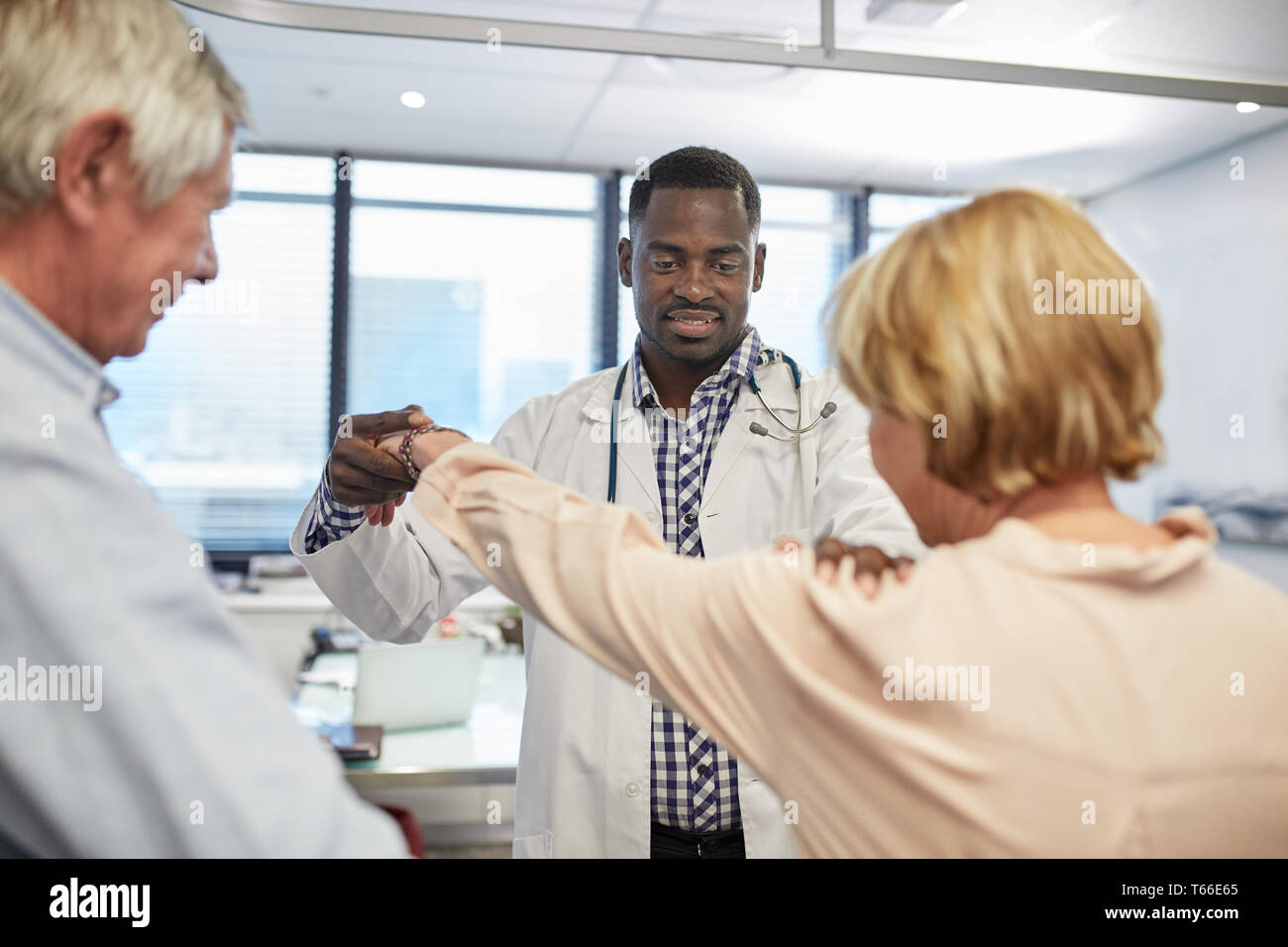 Medico maschio esame di pazienti anziani di spalla nella clinica sala esame Foto Stock