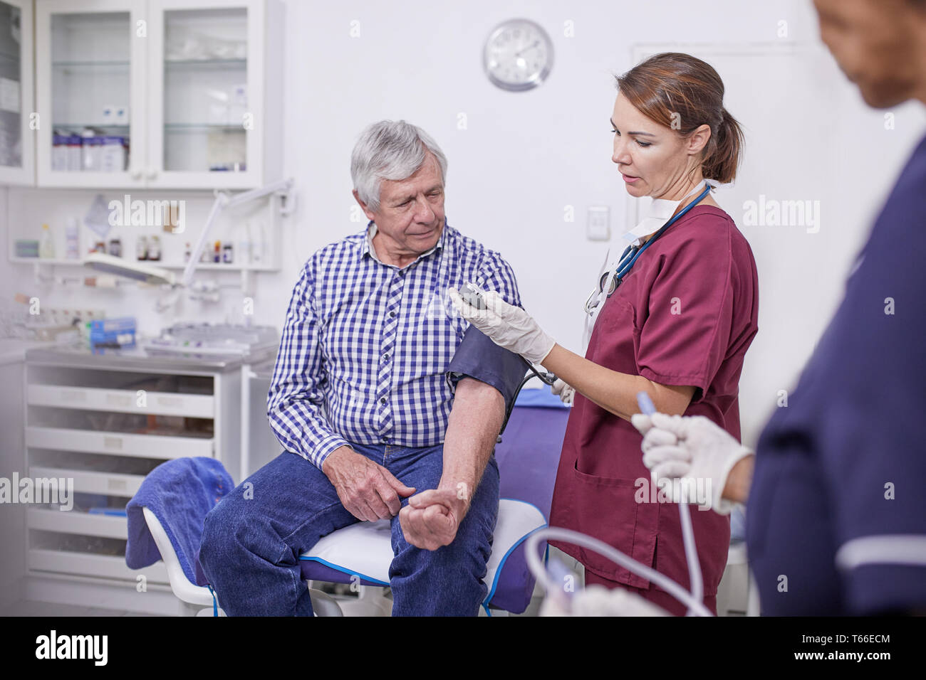 Medico controllando la pressione del sangue del paziente senior in clinica sala esame Foto Stock