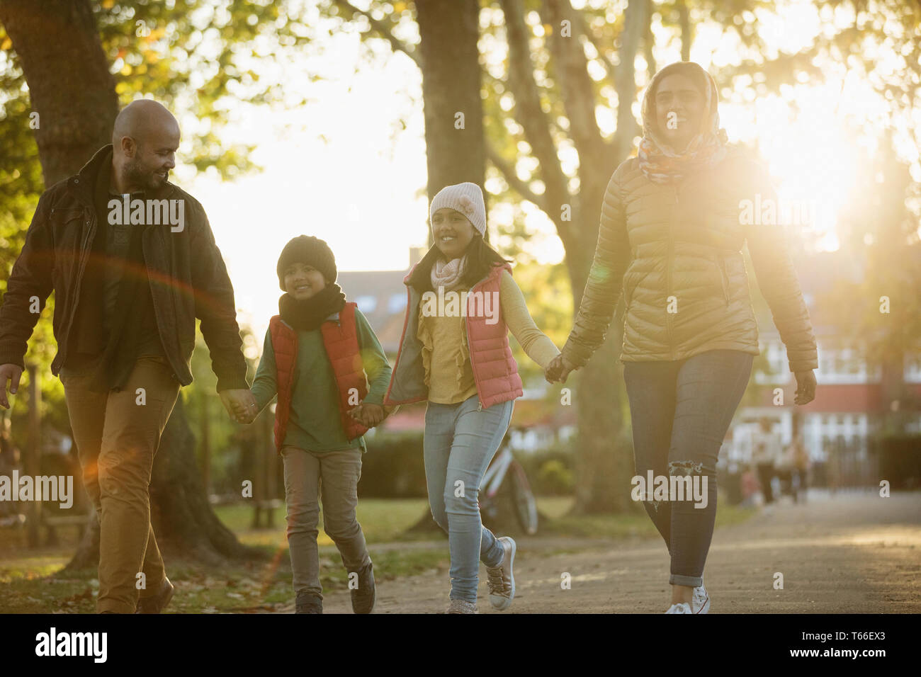 La famiglia felice Holding Hands, passeggiate nella soleggiata autunno park Foto Stock