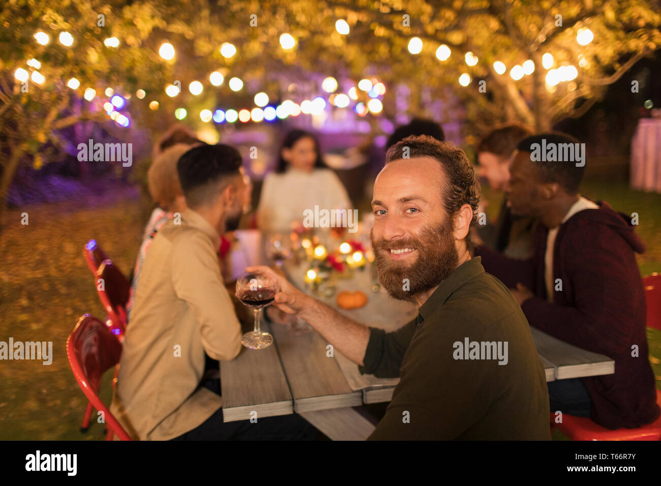 Ritratto fiducioso uomo beve vino, godendo la cena party in giardino Foto Stock