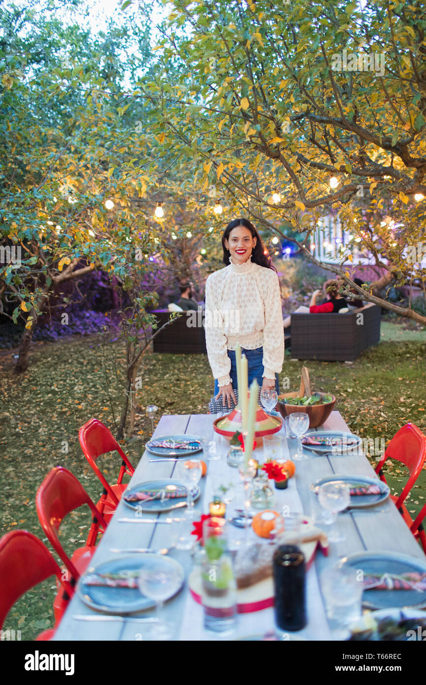 Ritratto di donna fiducioso che ospita la cena party in giardino Foto Stock