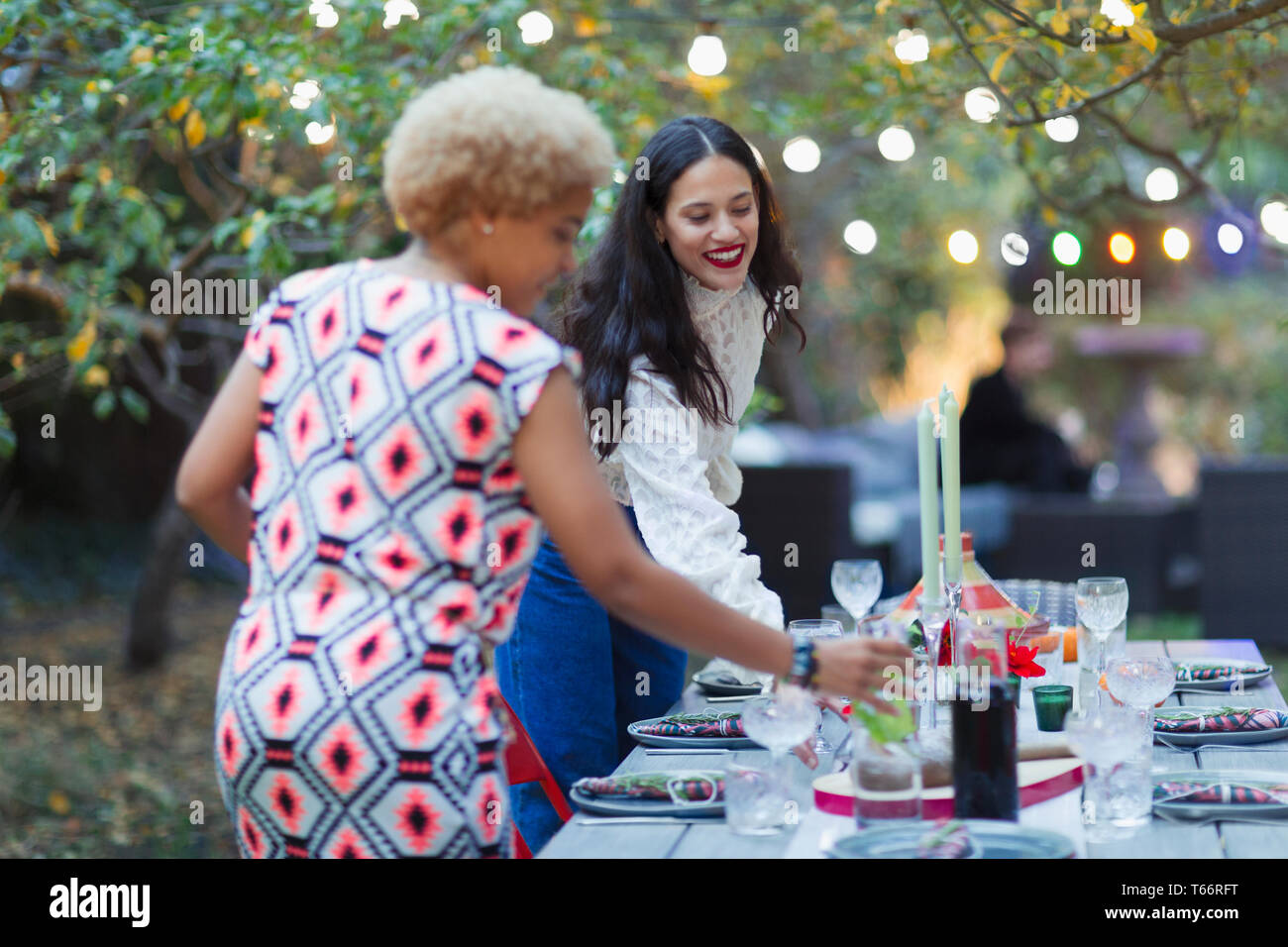 Le donne amici nella tabella di impostazione per la cena party in giardino Foto Stock