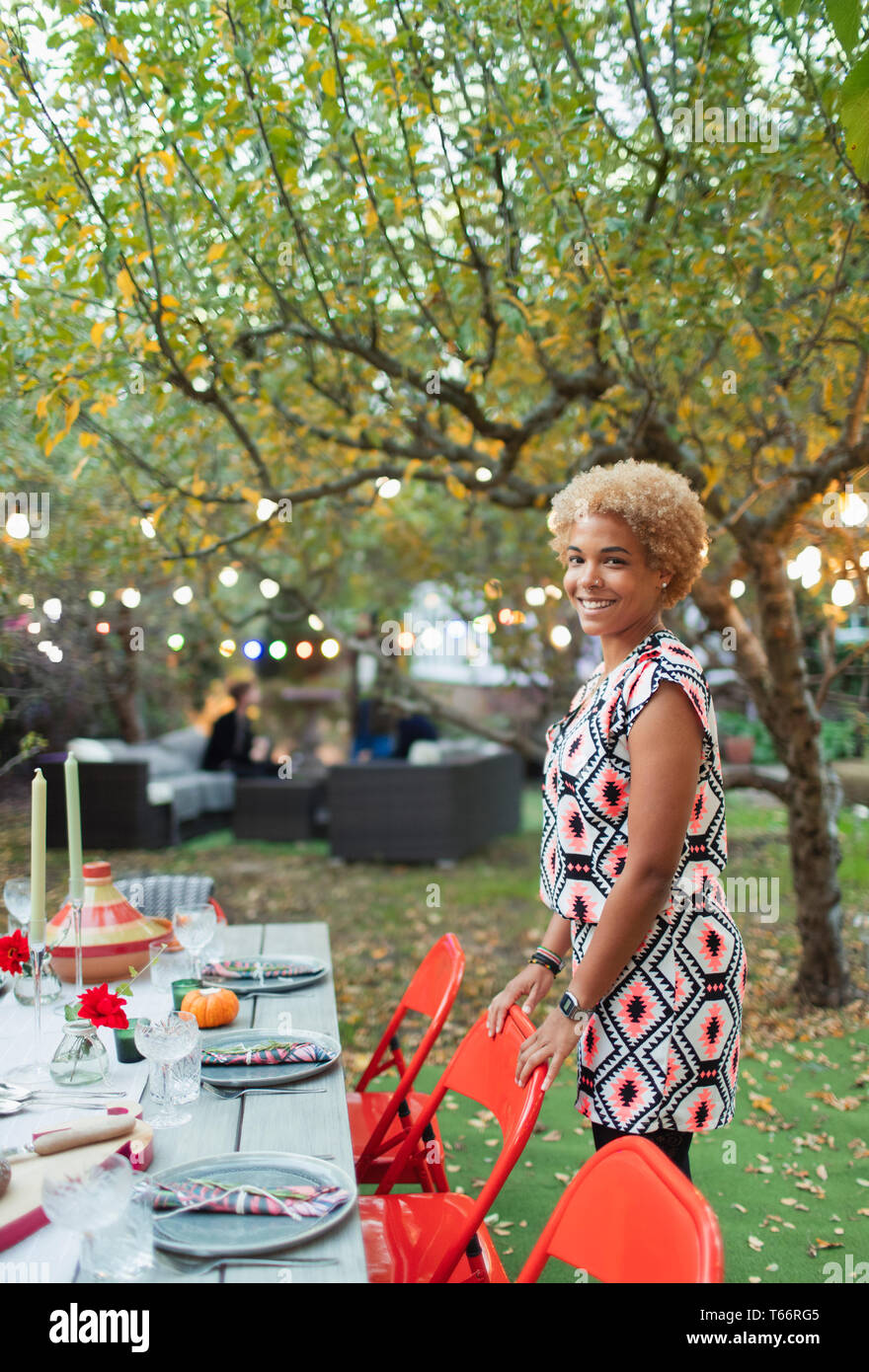 Ritratto di donna felice hosting dinner party in giardino Foto Stock