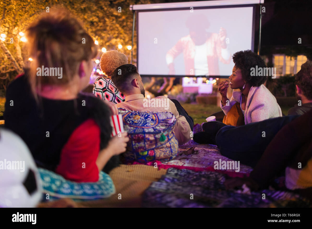 Gli amici a guardare film su schermo di proiezione nel cortile posteriore Foto Stock