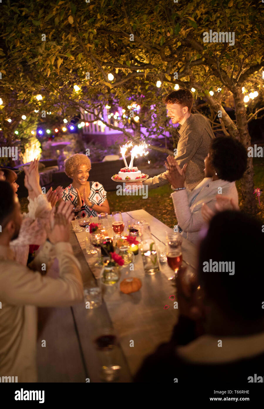 Amici festeggia il compleanno con sparkler torta al party in giardino Foto Stock