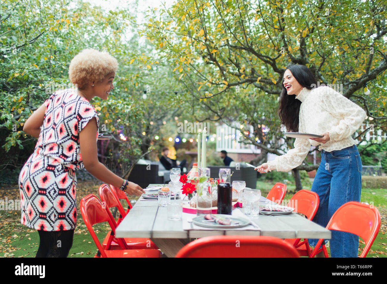 Le donne amici preparando la tabella per la cena party in giardino Foto Stock