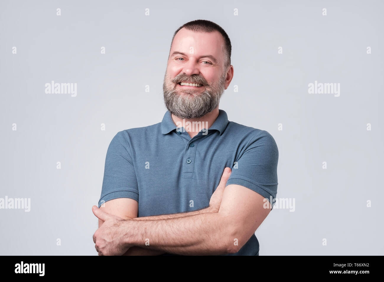 Affascinante uomo bello tenere le braccia incrociate e laufhing essendo convinto. Foto Stock