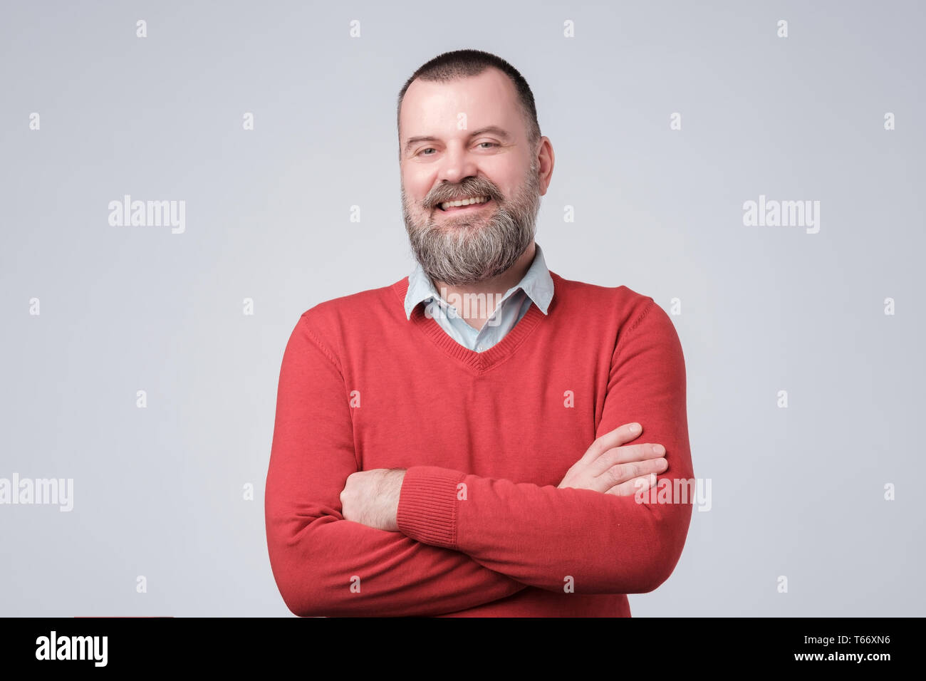 Affascinante uomo bello tenere le braccia incrociate e laufhing essendo convinto. Foto Stock