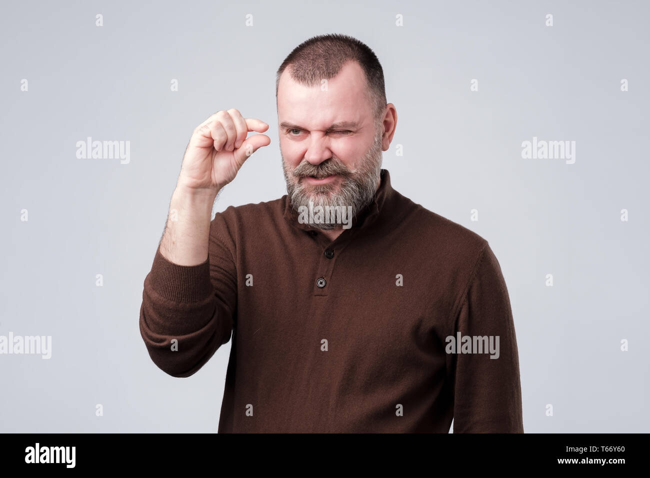Uomo maturo mostra qualcosa di invisibile essendo arrabbiato. Foto Stock