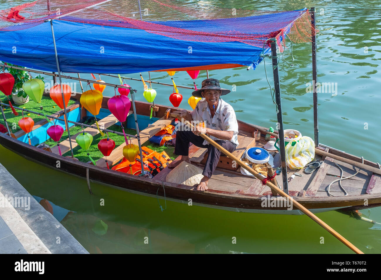 Vietnameses pescatore seduto nella sua barca da pesca decorata con lampioncini colorati, sul figlio Thu Bon River, Hoi An, Quang Nam Provence, Vietnam, ASI Foto Stock