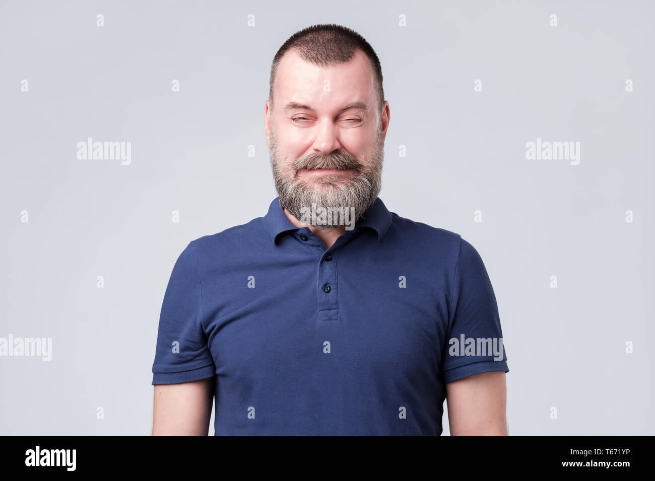 Uomo maturo in maglietta blu stropicciato a causa di sapore amaro. Foto Stock