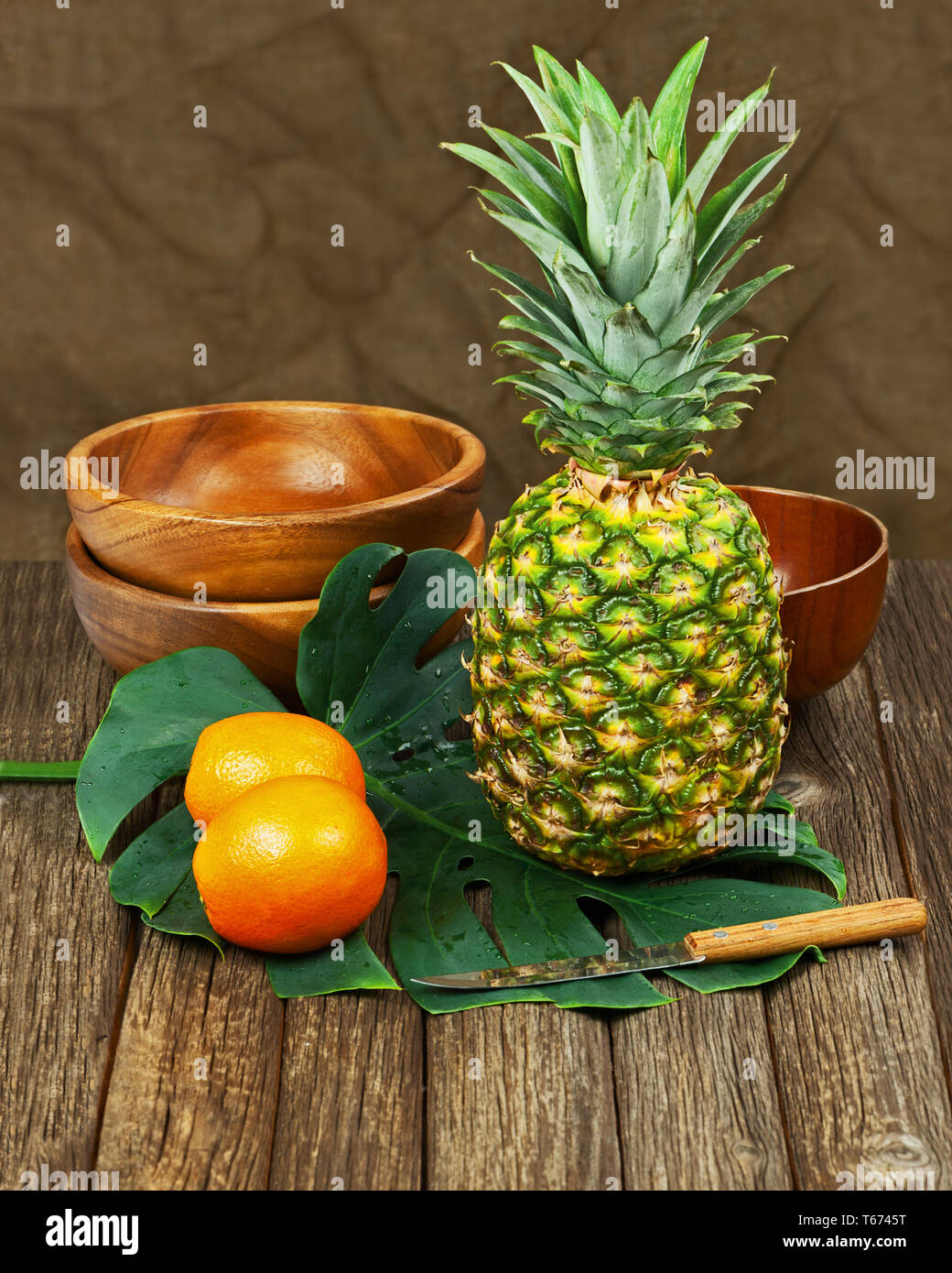 Natura morta con ananas e arance su sfondo di legno. Foto Stock