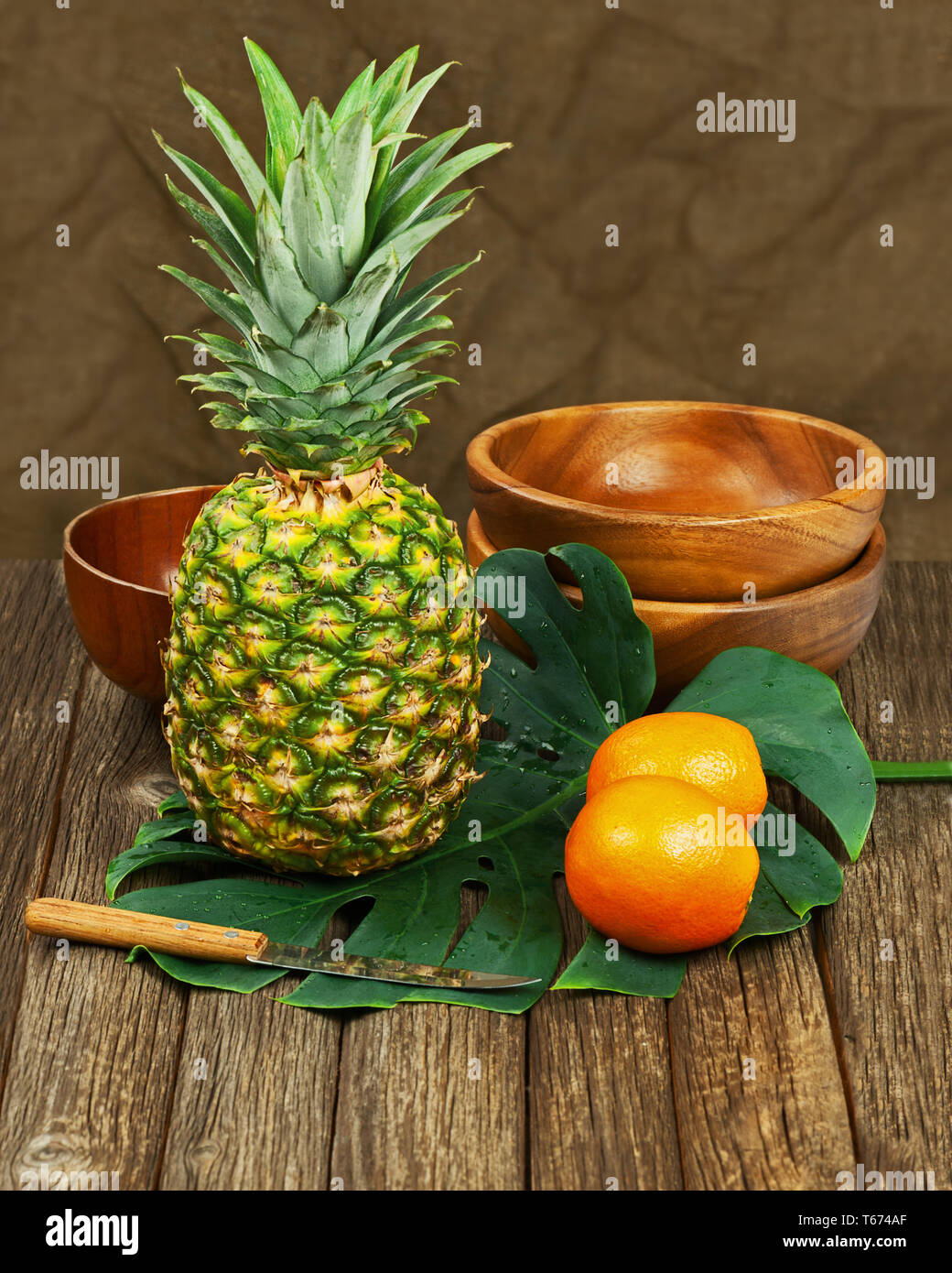 Natura morta con ananas e arance su sfondo di legno. Foto Stock